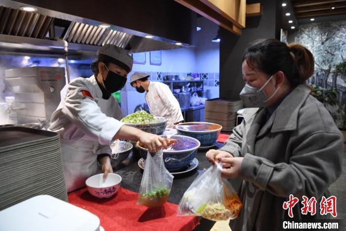 资料图:日前返回兰州的务工人员,为食客打包牛肉面。 杨艳敏 摄  中国饭店协会:现金流成餐企最大问题,但未来可期