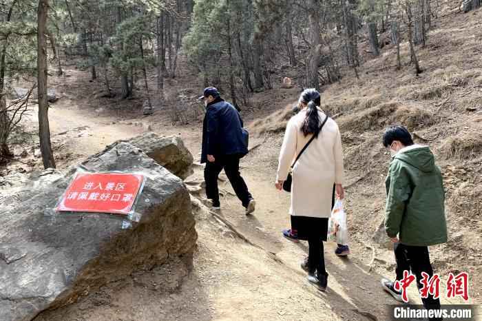 景区内张贴了许多防疫宣传标语,游客带着口罩游玩。 李佩珊 摄  贺兰山间春风起 游客理性踏青游